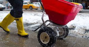 Salt spreader distributing salt on public sidewalks for winter maintenance and safety.
