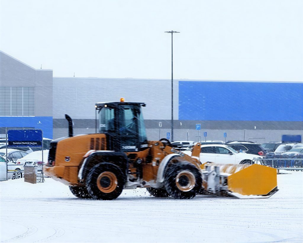 12312312-e1759081325420 (1) Snow removal equipment working in a pcommercial parkeing l;ot.